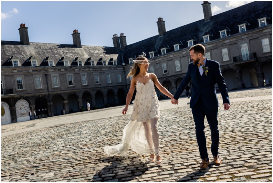 Bride and Groom walk hand in hand across the courtyard at the Royal Hospital Kilmainham