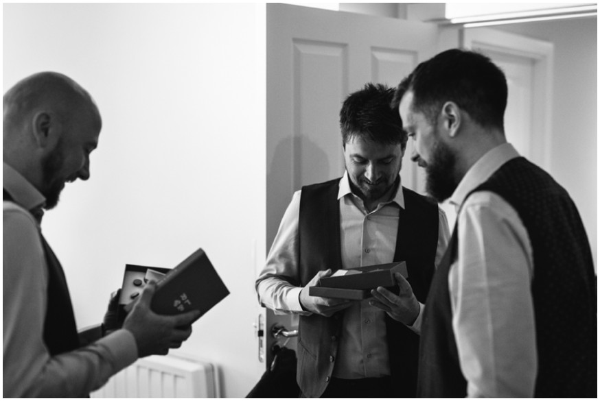 Groomsmen exchange gifts while getting ready 