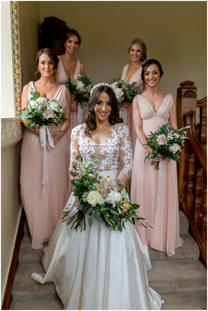 Bride and Bridesmaids in peach dresses stand on the stairs 