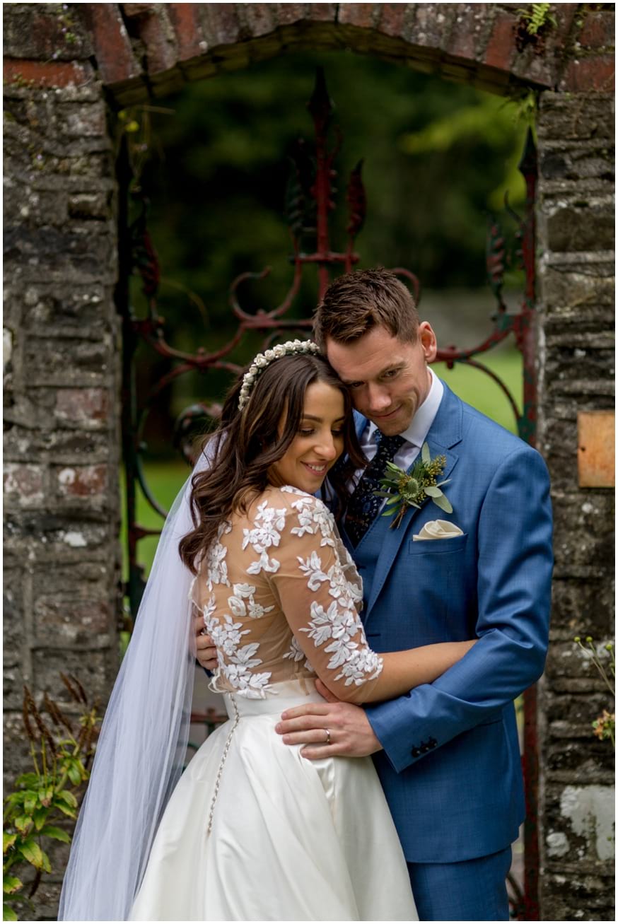 Bride and groom embrace in a stone arch doorway in the walled gardens at Tankardstown