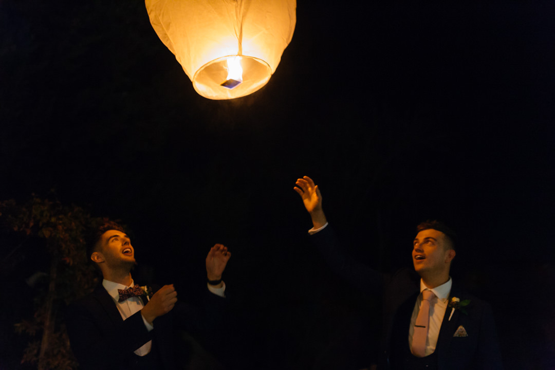 Grooms release a fire lantern at their wedding reception