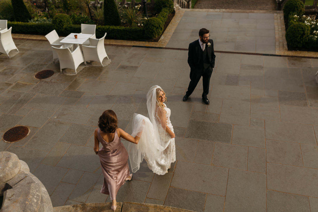 Bridesmaid helps the bride with her train in gardens at the elegant Markree Castle 